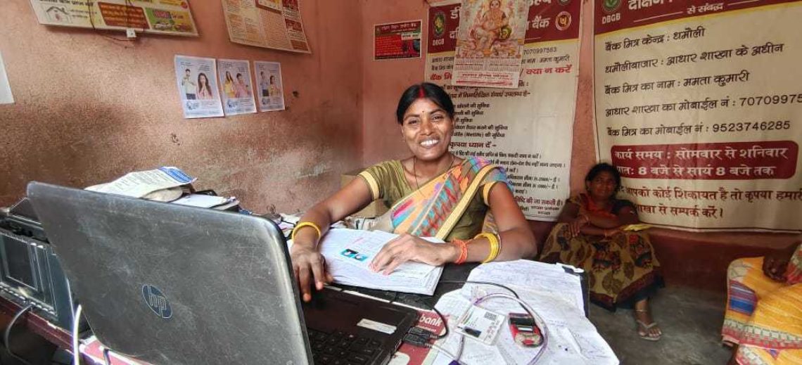 Malti, a Community Agent in Bihar, India, sits at her desk with a laptop. She is smiling at the camera.