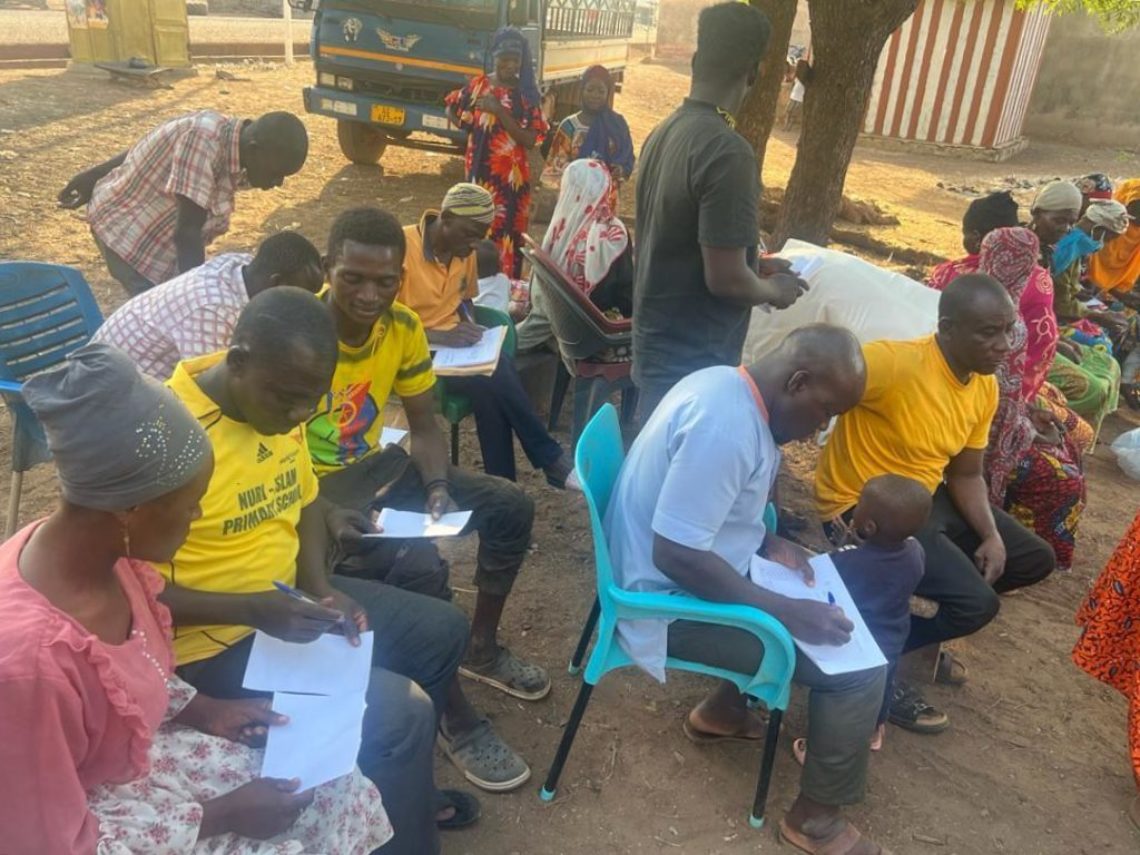 A group of men in Ghana are seated outside to engage in a Grameen Foundation facilitated Workshop called Exploring Power Dynamics