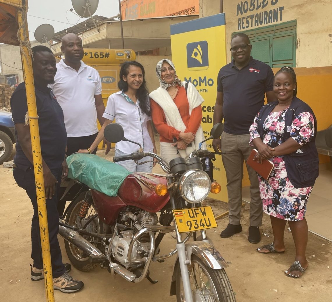 Grameen Foundation team members stand around a motorcycle in Uganda