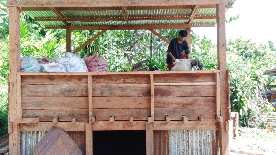 Grameen Foundation partners sort coconut meat that is stored on a re-drying facility made of wood