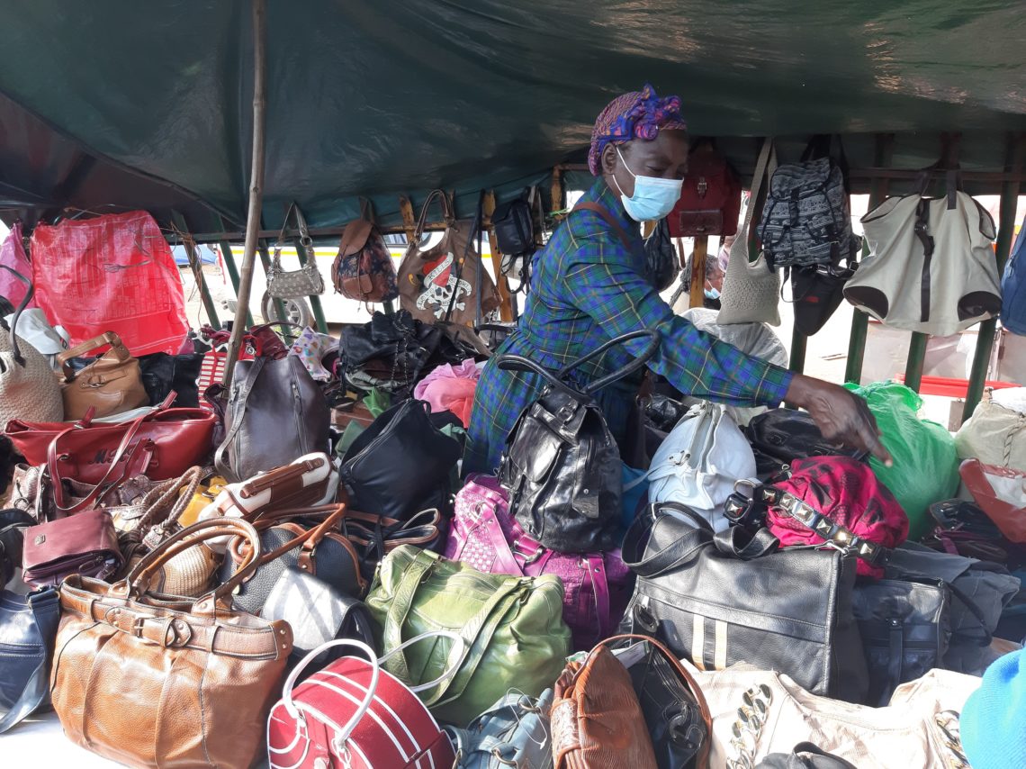 Masked woman displaying purses at market