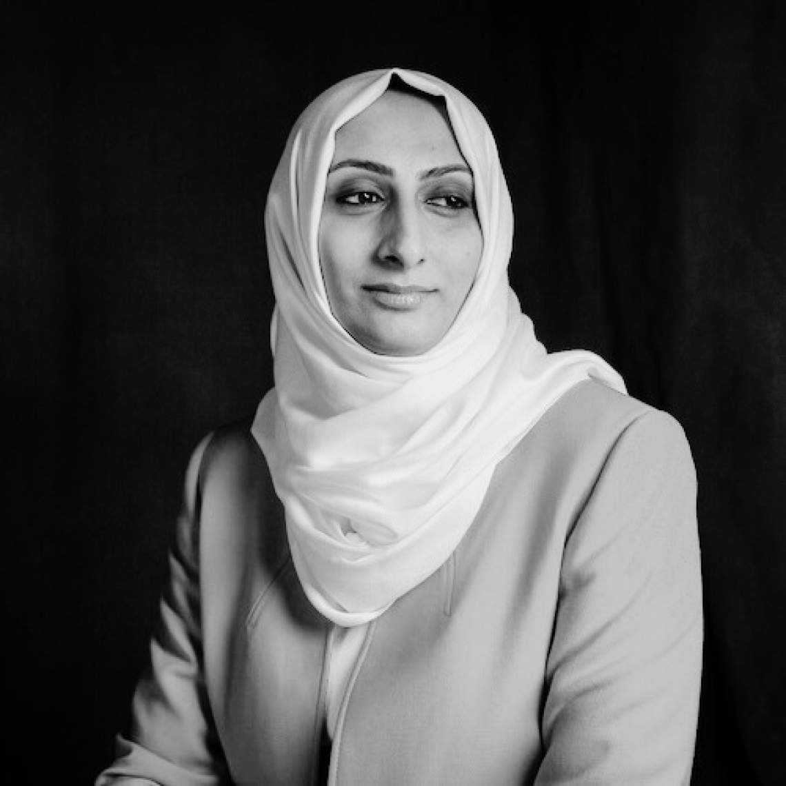 Grameen Foundation President and CEO Zubaida Bai is seated and wearing a jacket with a white head scarf