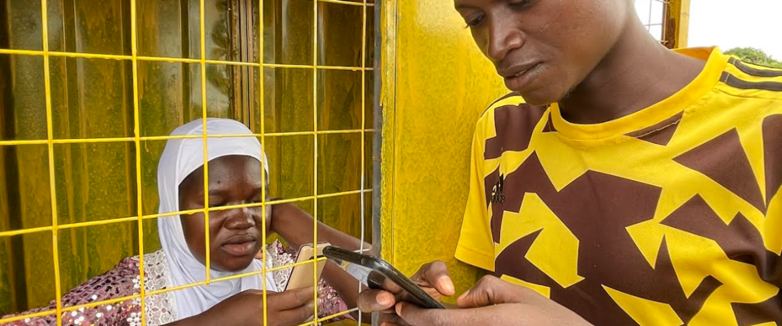 Ayisha, a Grameen Agent in northern Ghana, assists a client in her kiosk.