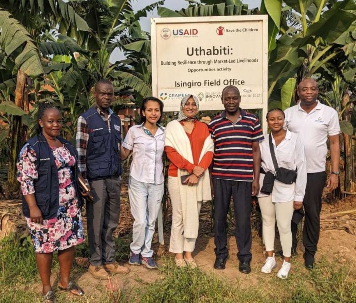 A group photo of the Grameen Foundation team standing in front of the Uthabiti Refugee Settlement