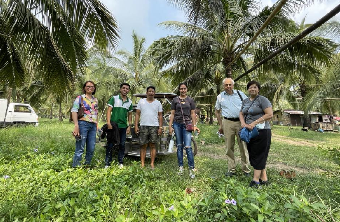 F2F volunteer Jay Ahuja stands with GreenLife members in a coconut grove