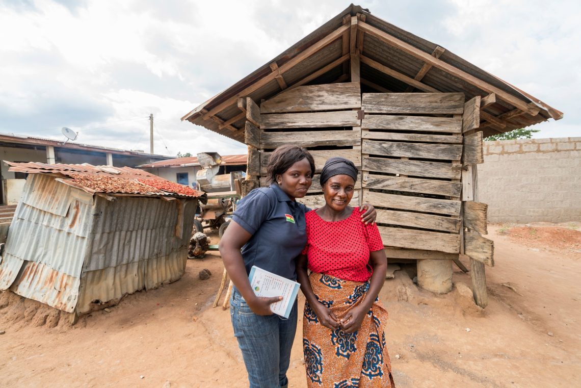 Grameen Community Agent Rachael Dersi hugs her client, smallholder farmer Grace, on her farm in Ghana