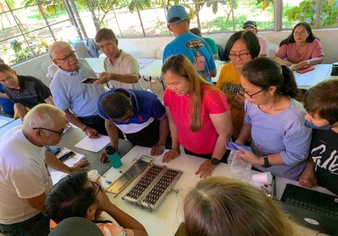 Joyce and participants gathered around a table, examining cacao beans.