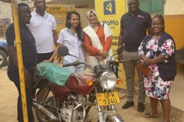 Grameen Foundation team members stand around a motorcycle in Uganda