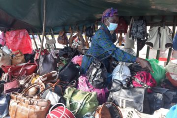 Masked woman displaying purses at market