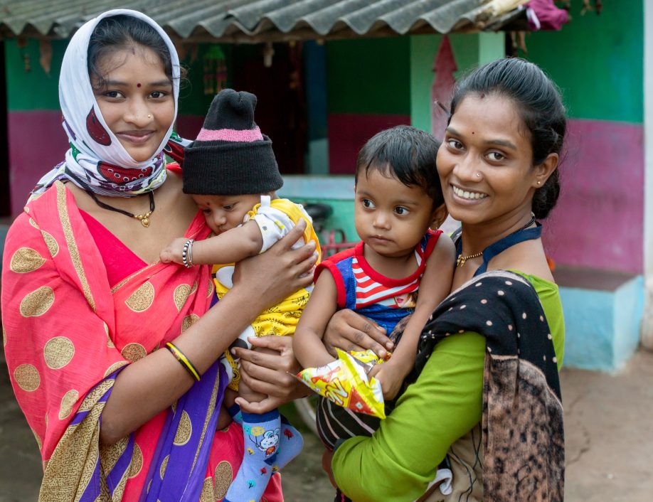 Indian Community Agent and client holding their children and smiling