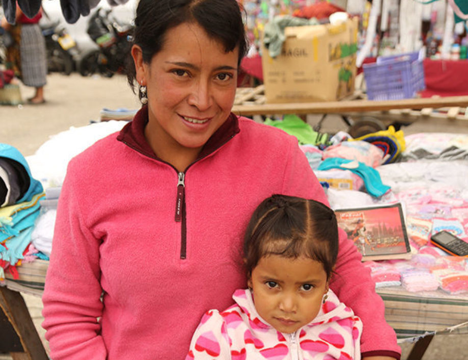 Teresa, a RICHES group participant from El Salvador, and her daughter. Teresa is wearing a pink sweater, and her daughter is wearing a white sweater with pink hearts.