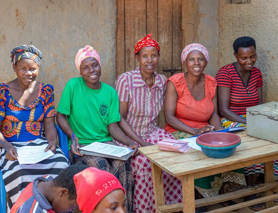 Grameen Foundation Refugee Finance Program supports women savings groups. This photos shows one of the savings group of five women seated at a table outside.