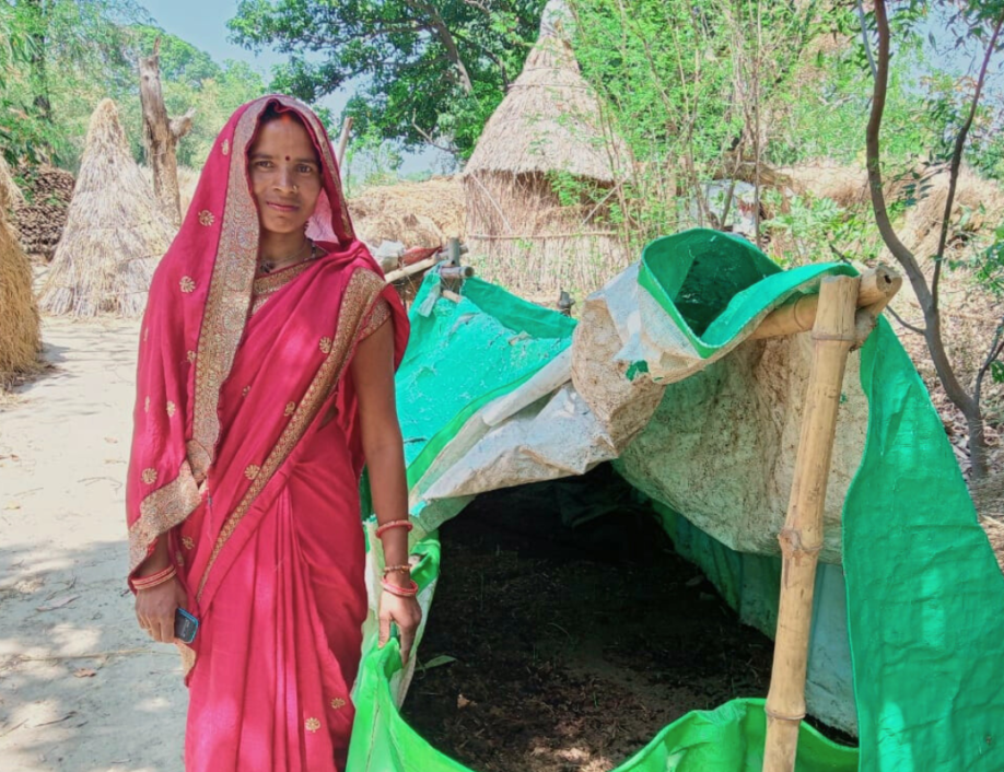 A woman stands next to a large green bag of soil