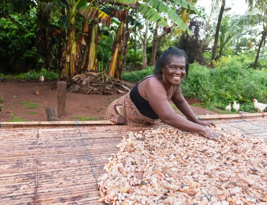 A woman stands outside in front of a large table covered in husks